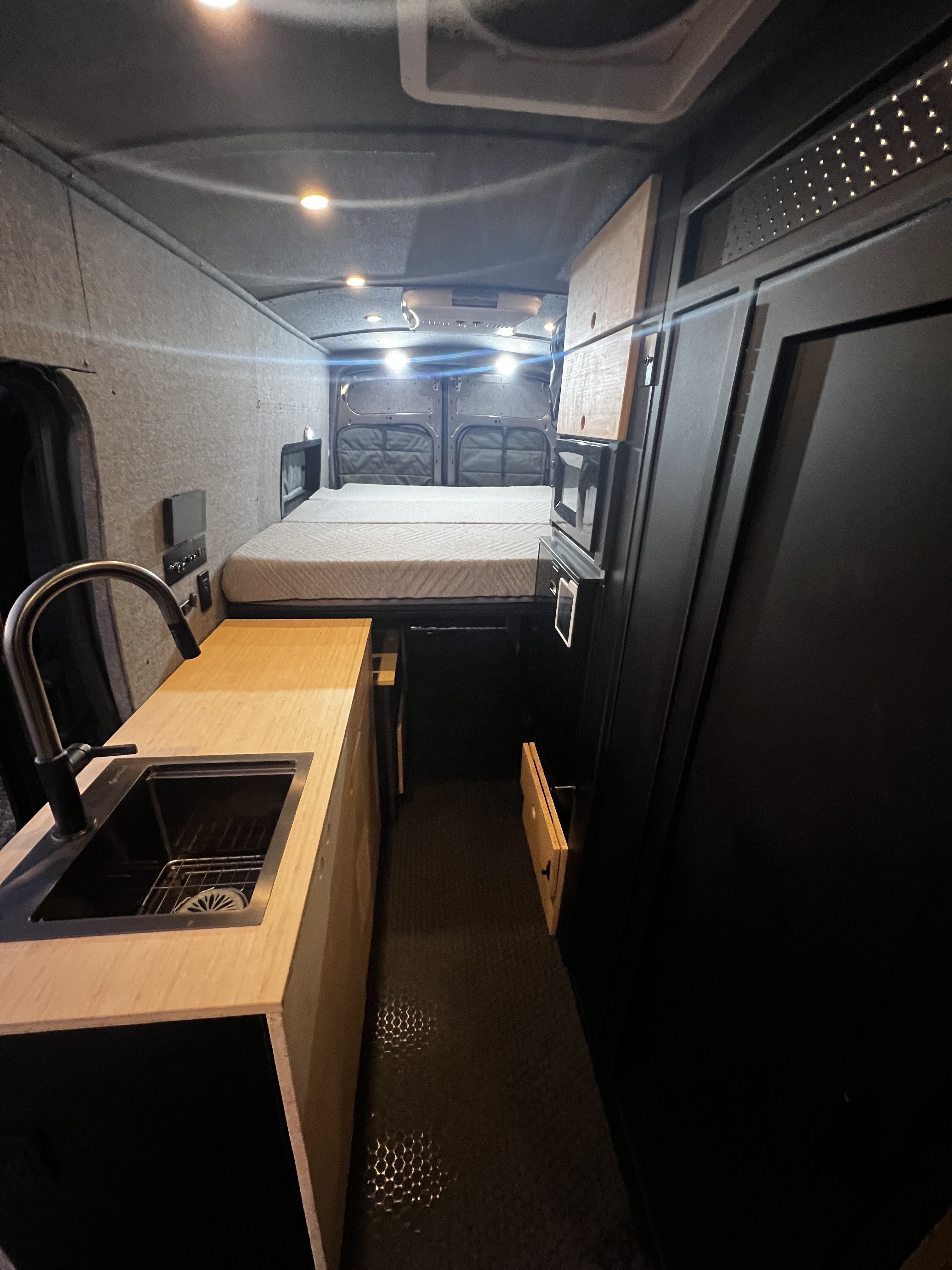Compact galley kitchen in an OZK adventure van with water system and storage.