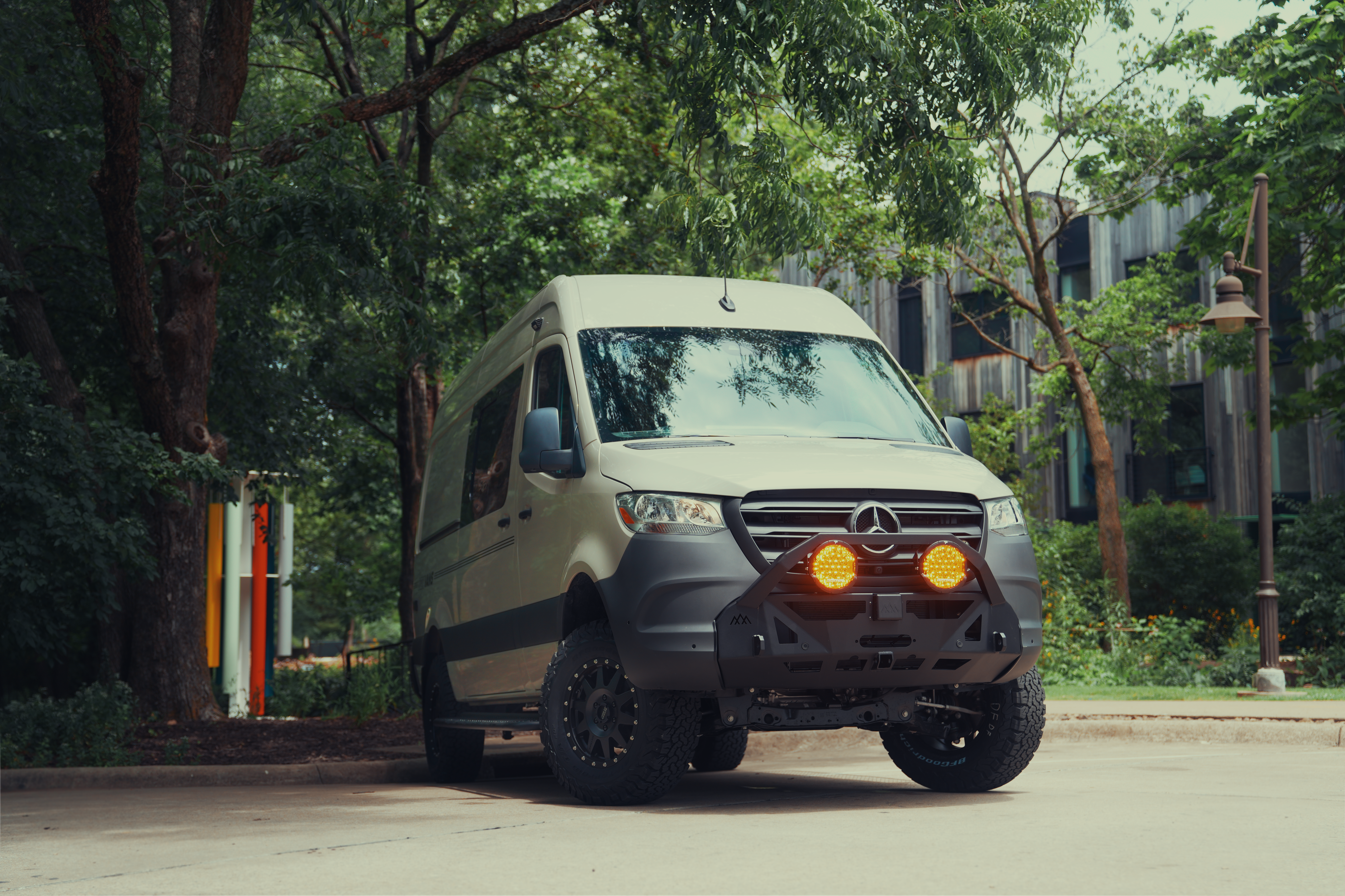 A custom camper van built by OZK Customs parked near a mountain trail.